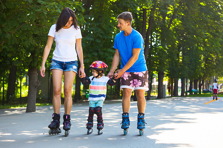 Cute baby boy and his mom learning inline skating with skating i